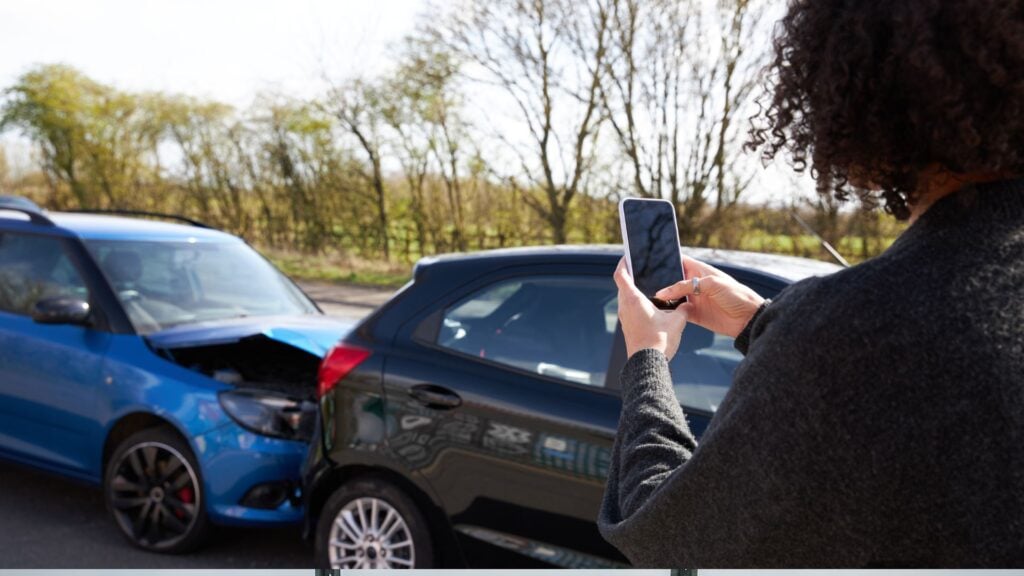 Person photographing car accident scene in Louisiana for UM/UIM claim documentation.